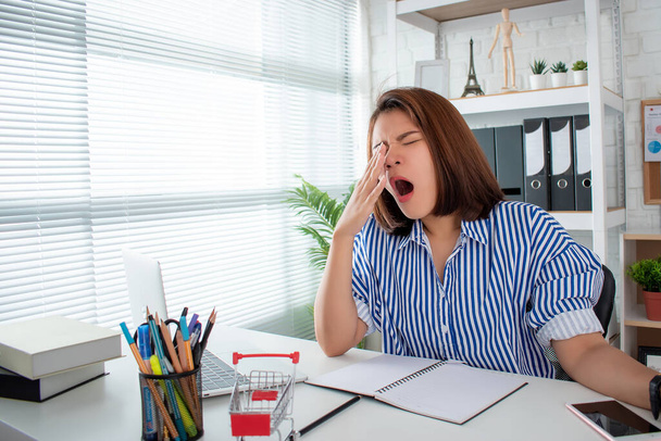 Woman yawning and sleepy at an office desk, overwork and sleep deprivation concept. - Valokuva, kuva