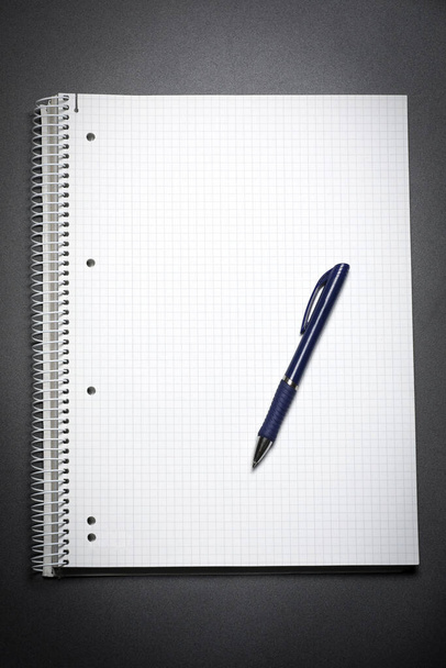 Vue à plat d'un cahier blanc et d'un stylo bleu sur une table noire. Espace de copie. Stratégie de marketing. Solution d'entreprise. - Photo, image