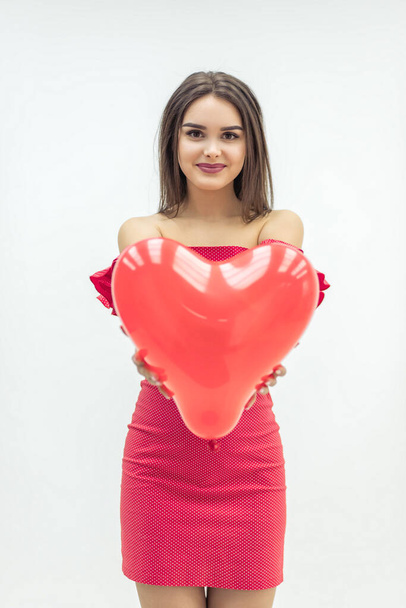 Lovely girl fell in love and expresses her tender feeling giving a heart balloon to her lover. - Photo, image