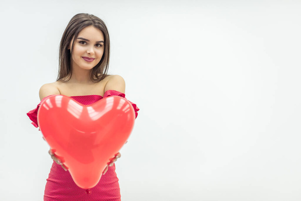 Smiling woman stands over white background with red heart-shape balloons in hands. - Photo, image
