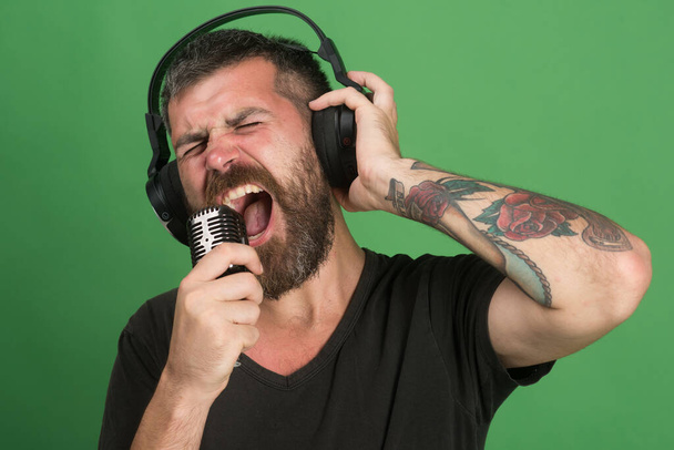 Singer with beard and excited face listens to music. - Φωτογραφία, εικόνα