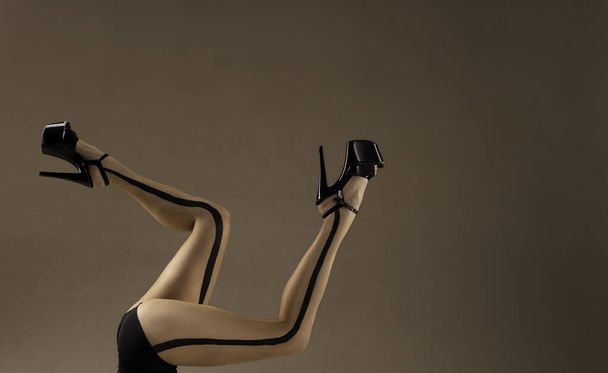 women's long legs in black high heels in a beautiful pose isolated on the background - Fotoğraf, Görsel