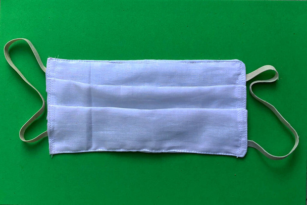 Beschermend gezichtsmasker geïsoleerd op groene achtergrond - Foto, afbeelding