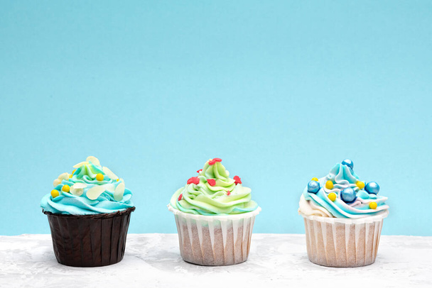 Colourful cupcakes decorated by caramel candies on blue background. Horizontal with space for text - Photo, image