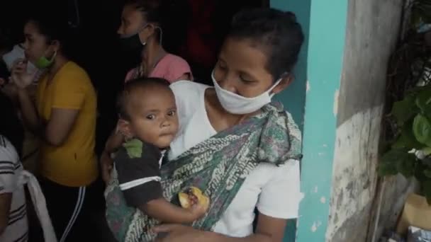 Benoa, Kuta, Kabupaten Badung, Bali, Indonesia - July 8, 2020: Video of a small village in Indonesia with masked people and children on their faces - Video