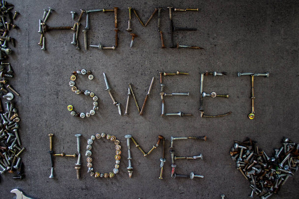 Home sweet home sign made of old bolts on dark grey textured background. Home renovation concept.  - Photo, Image