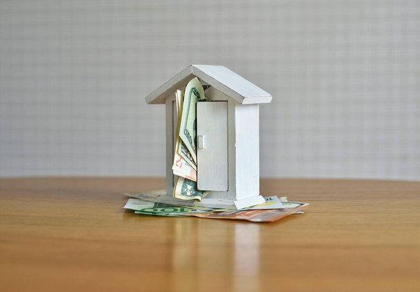 χρήματα και το μοντέλο σπίτι στο τραπέζι. έννοια σχετικά με το θέμα της κατασκευής και του χρήματος - Φωτογραφία, εικόνα