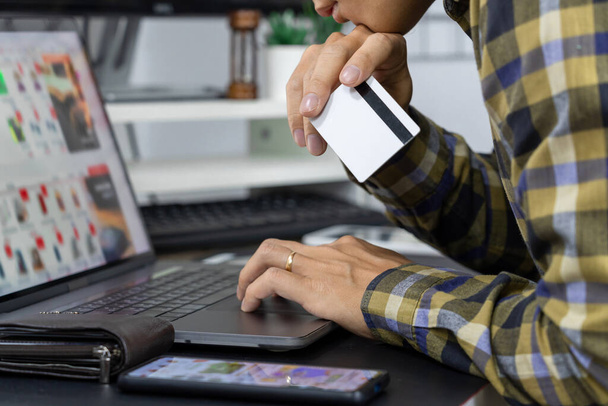 Asiatische Mann mit Kreditkarte und Eingabe von Informationen im Internet mit Laptop zu Hause, Online-Shopping-Konzept - Foto, Bild