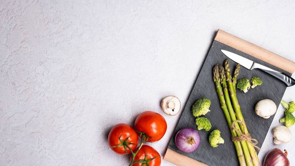 Grupa organicznych świeżych warzyw - zielone szparagi, brokuły, grzyby na szarym tle, płaskie nioski. Pojęcie zdrowej żywności wegetariańskiej, diety i domowej kuchni. Widok z góry, przestrzeń kopiowania. - Zdjęcie, obraz
