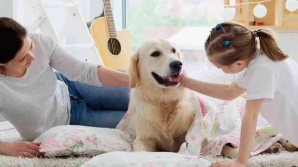 Mother and daughter palming dog on bedding - Imágenes, Vídeo