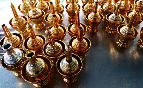 Gruppo di bottiglia d'oro e ciotola su vassoio rosso per versare acqua di dedizione ai morti al tempio thailandese. - Foto, immagini