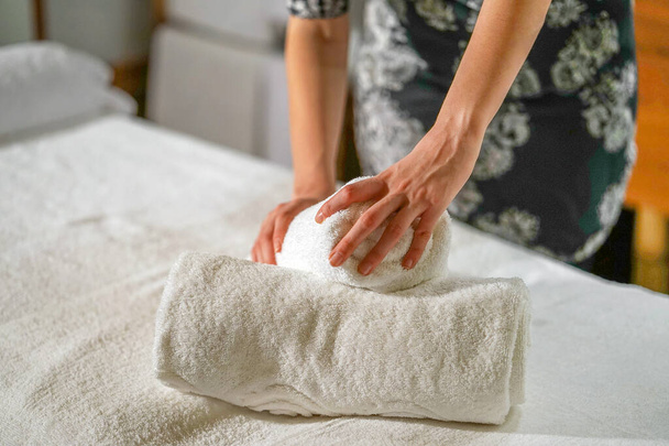 Ręce kobiety składa ręcznik, przygotowuje miejsce pracy w spa dla recepcji klientów. Pokojówka przygotowuje pokój do salonu spa. Koncepcja zdrowia i piękna. - Zdjęcie, obraz