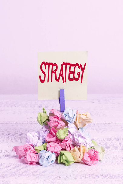 Word writing text Strategy. Business-Konzept für Aktionsplan oder Strategie entwickelt, um ein übergeordnetes Ziel zu erreichen Erinnerungsstapel farbige zerknüllte Papier Wäscheklammer Erinnerung weißen Holzraum. - Foto, Bild
