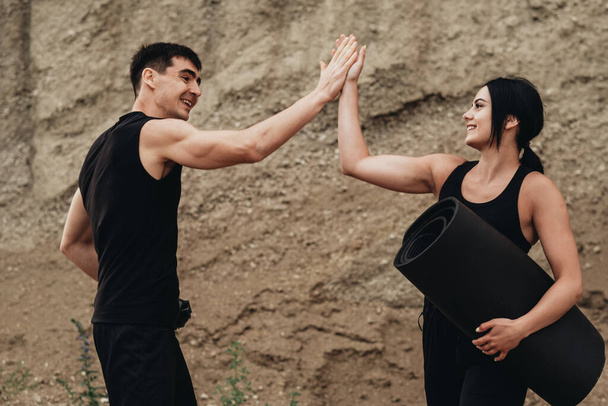 Two Athletes in Black Sportswear Giving High Five After Training Together Healthy Lifestyle and Outdoor Workout Concept - Photo, Image