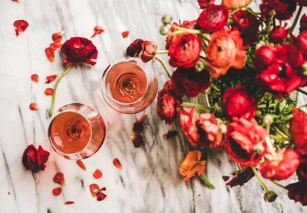 Flat-lay of rose wine in glasses and red spring blossom flowers bouquet over white marble background, top view. Wine shop, bar, wine tasting, wine list concept - Foto, imagen