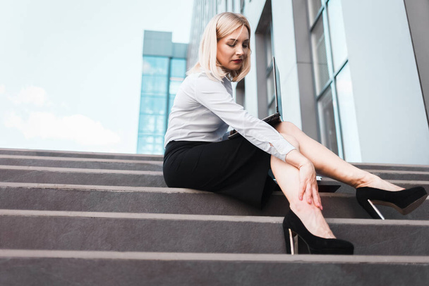 Trabajadora de oficina sufre de dolor en las piernas debido al uso de tacones. Consecuencia del uso del concepto de zapatos de tacón alto
 - Foto, imagen