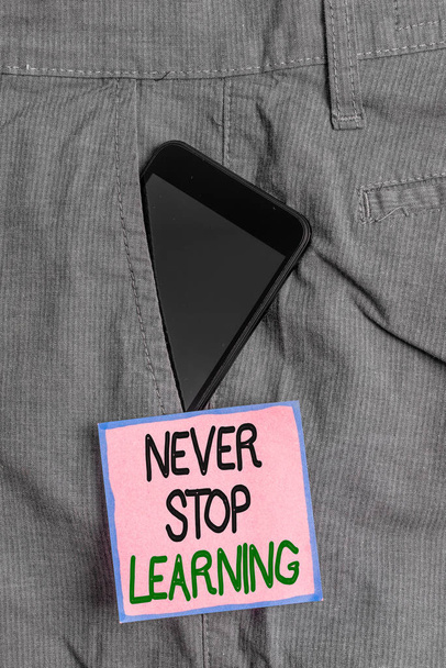 Konceptualne pismo ręczne pokazujące "Never Stop Learning". Biznesowe zdjęcie pokazujące ciągłą edukację i techniki, aby być konkurencyjnym urządzeniem Smartphone wewnątrz spodnie przedni papier kieszonkowy. - Zdjęcie, obraz