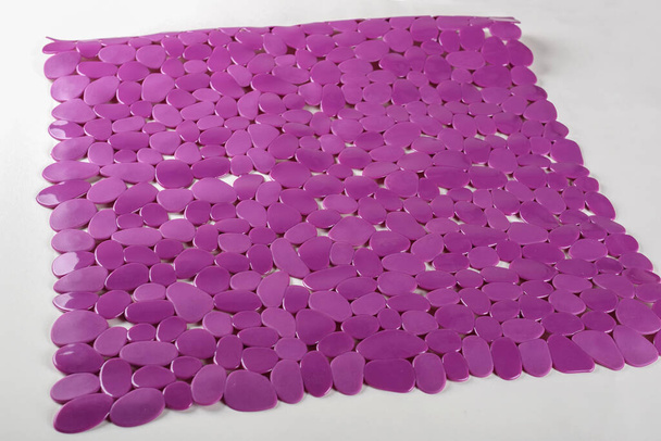 Фіолетовий гумовий килимок для ванни з візерунком як фон. Фіолетовий гумовий килимок з відсмоктувальними чашками та отворами проти ковзання для дитячої ванни
 - Фото, зображення