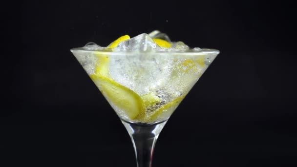 Sparkling water with lemon and ice, white soda in glass on black background, refreshing cold drink - Footage, Video