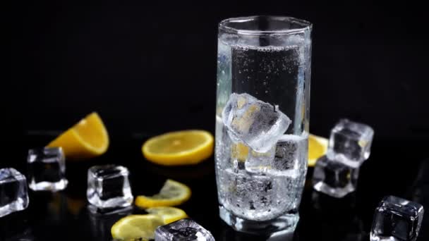 Szénsavas víz vagy koktél citrommal és jéggel, fehér szóda üvegben fekete alapon, frissítő hideg ital - Felvétel, videó