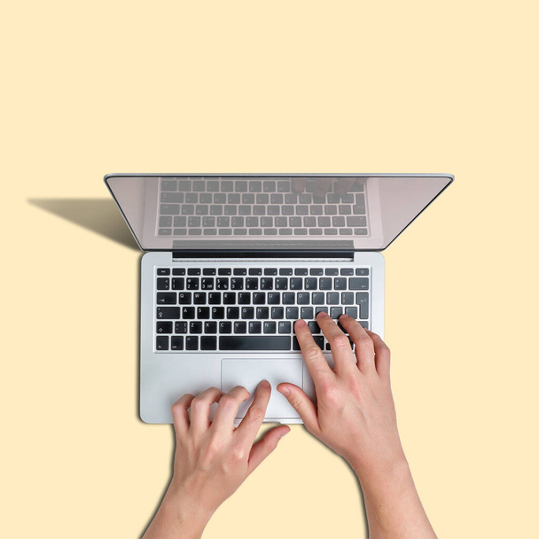 Una persona utilizza un computer portatile su uno sfondo giallo - Foto, immagini