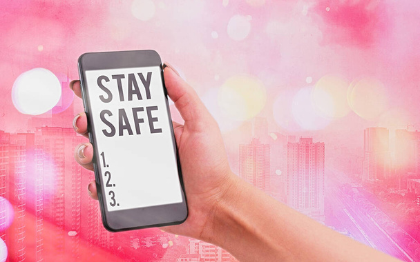 Handwriting text Stay Safe. Concept meaning secure from threat of danger, harm or place to keep articles Modern gadgets with white display screen under colorful bokeh background. - Photo, Image