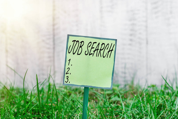 Conceptual hand writing showing Job Search. Business photo showcasing an act of sourcing for job openings and apply for a position Plain paper attached to stick and placed in the grassy land. - Foto, Imagem