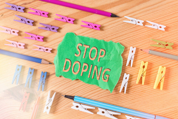 Eine schriftliche Notiz mit der Aufschrift Stop Doping. Geschäftliches Foto, das den Verzicht auf die Verwendung verbotener leistungssteigernder Medikamente zeigt Farbige Wäscheklammern leeren Mahntafel Holzboden Hintergrund Büro. - Foto, Bild