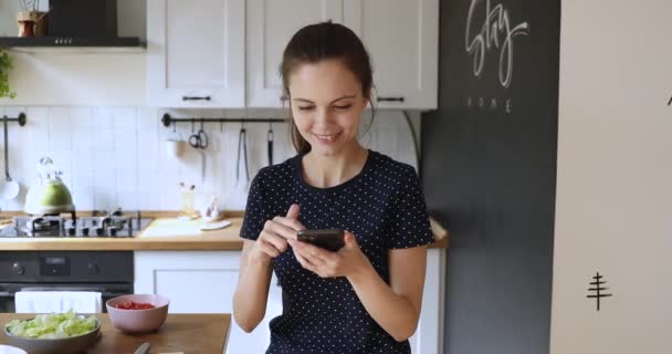 Woman holding smartphone using cooking apps search recipes in internet - Filmagem, Vídeo