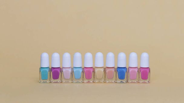 Colored nail polish in a row. Isolate on beige - Fotoğraf, Görsel