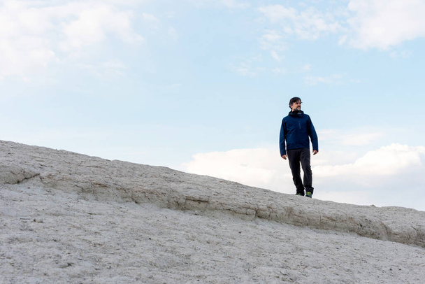 Od dołu dorosły turysta stojący na szczycie wzgórza w Kapadocji, Turcja. - Zdjęcie, obraz