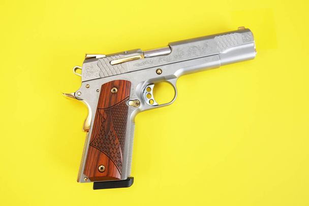 pistool of pistool ingelegd met hout en goud geïsoleerd op een gele achtergrond. wapenconcept. bescherming en geweld. - Foto, afbeelding