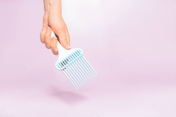 Had holding comb tool under trendy color background with copy space and soft light. Stylish Professional Barber hair cut tools, Hairdresser salon concept, Haircut accessories. - Foto, afbeelding