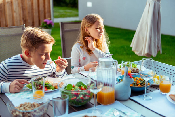Szczęśliwa rodzina z dwójką nastolatków jedzących zdrową kolację razem na tarasie - Zdjęcie, obraz