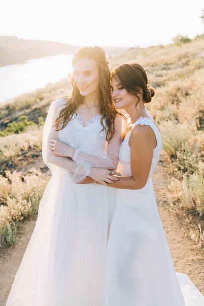 Pareja de boda lesbiana en vestidos blancos
 - Foto, imagen