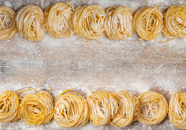 Frische Nudelgerichte. Hausgemachte italienische Pasta auf einem hölzernen Hintergrund in rustikalem Stil mit Ei und Mehl dekoriert. - Foto, Bild