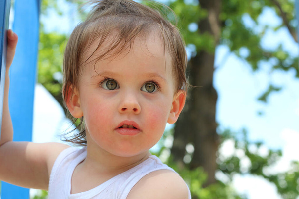 Una mirada penetrante de una niña blanca con el pelo acariciado al aire libre. Pequeño bebé con ojos muy hermosos
. - Foto, imagen