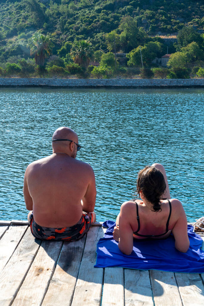Coppia seduta sul molo da dietro in giornata di sole. - Foto, immagini