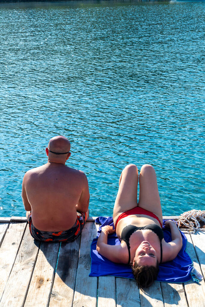 Paar sitzt bei sonnigem Wetter von hinten auf der Seebrücke. - Foto, Bild