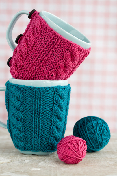Две синие чашки в голубом и розовом свитере с клубком пряжи
 - Фото, изображение