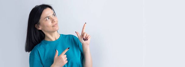 Onnellinen nuori valkoihoinen nainen sinisessä t-paidassa osoittamassa sormella pois - Valokuva, kuva