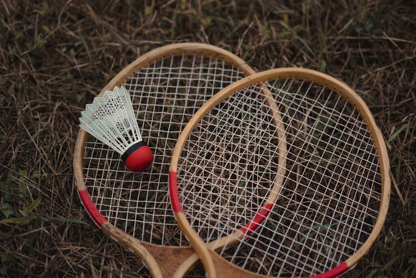 Raquetes de badminton de madeira e um vaivém de plástico branco com uma cabeça vermelha. O jogo de badminton. Hobbies e recreação ao ar livre. Conjunto de badminton para dois
. - Foto, Imagem