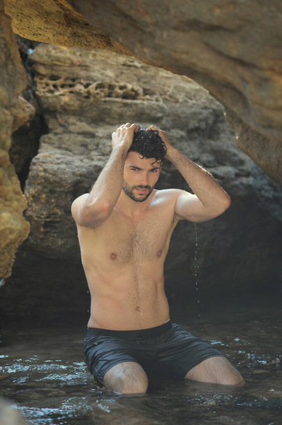 Young stylish man outdoor portrait near the sea and rocks, topless - Foto, immagini