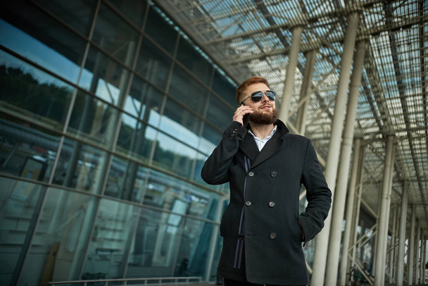 Urban business man in sunglasses talking smart phone traveling walking outside - Fotó, kép