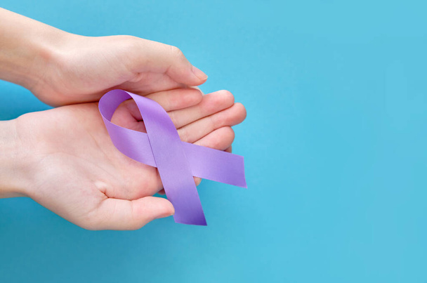 Purple lilac symbolic ribbon - the problem of Hodgkin's lymphoma. Two crossed hands on a blue background - Valokuva, kuva