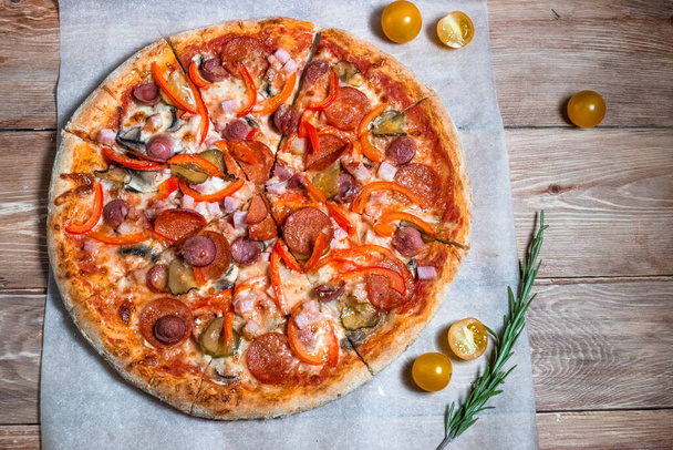 Appetizing pizza on a wooden table surrounded by herbs and spices. The concept of delicious food, restaurants and cafes - Φωτογραφία, εικόνα