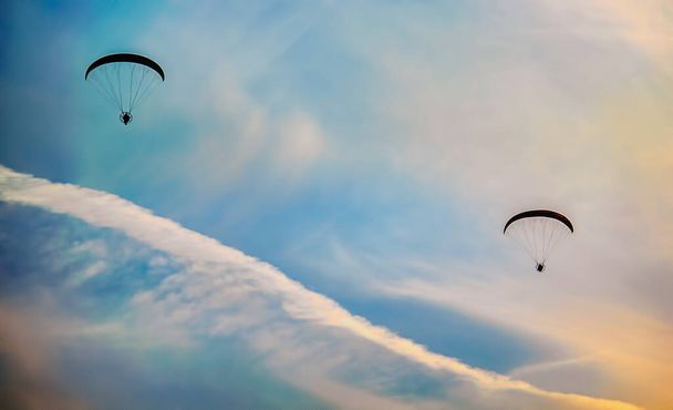 Duo de parapentes voando para o pôr do sol
 - Foto, Imagem