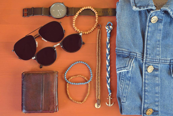 Top view of men accessories. Hipster or modern man concept. Accessories for going for a walk. Male fashion accessories, flat lay on coral pink background. Wallet, bracelets, sunglasses - shades, watch - Φωτογραφία, εικόνα