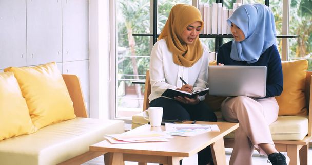 Due giovani imprenditrici musulmane discutono di un lavoro in ufficio. - Foto, immagini