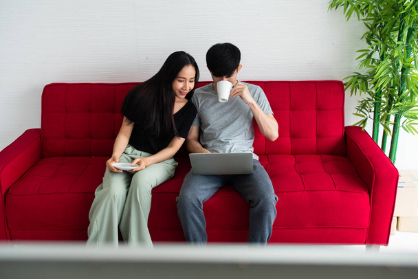 Happy Asian couple spending time together on sofa at home. - 写真・画像